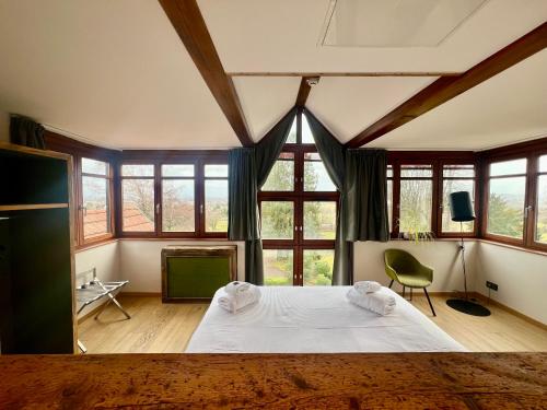 Schlafzimmer mit einem großen weißen Bett und Fenstern in der Unterkunft Hôtel La Garenne in Saverne