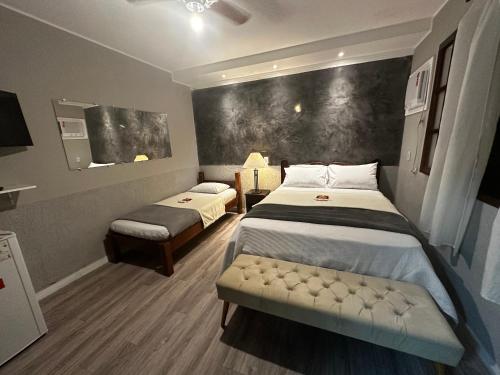 um quarto com duas camas e um banco em Pousada do Suiço em Saquarema