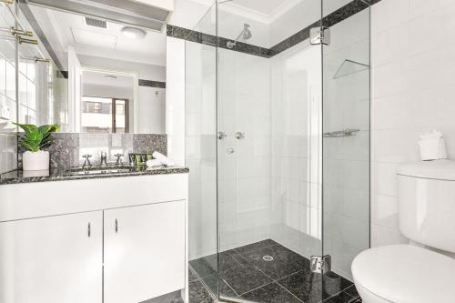 a white bathroom with a shower and a toilet at Waterfront Delight on Darling Harbour at Pyrmont in Sydney