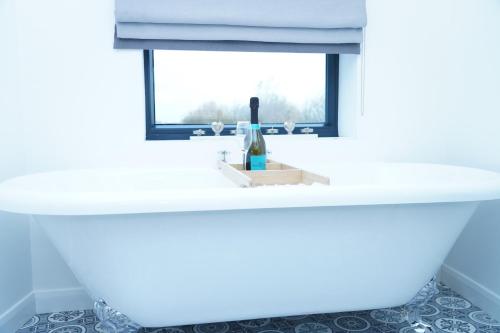 a white sink in a bathroom with a window at The Angel - Luxury Lakeside Lodge in Cotham