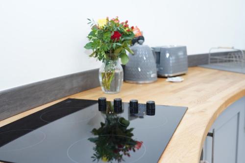 a kitchen counter with a vase with flowers in it at The Angel - Luxury Lakeside Lodge in Cotham