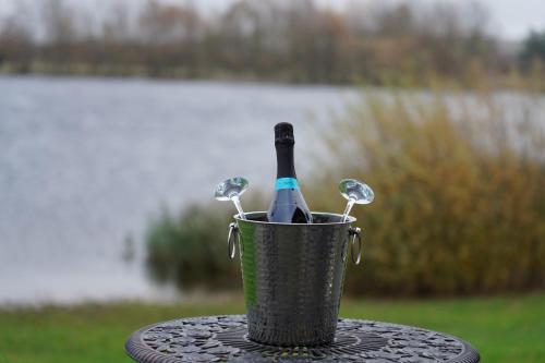 a bottle of wine in a bucket on a table at The Angel - Luxury Lakeside Lodge in Cotham