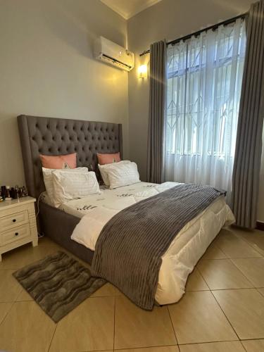 sypialnia z dużym łóżkiem i dużym oknem w obiekcie Stay with soniyah w mieście Dar es Salaam