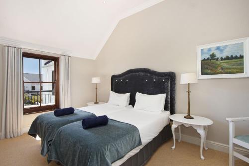a bedroom with two beds and a window at Winelands Golf Lodges 21 in Stellenbosch