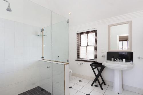 uma casa de banho branca com um lavatório e um chuveiro em Winelands Golf Lodges 21 em Stellenbosch