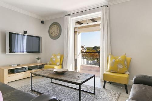 sala de estar con TV, mesa y sillas en Winelands Golf Lodges 24, en Stellenbosch