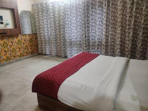 een slaapkamer met een bed met een rode en witte deken bij Hotel Rose Garden - Janakpuri in New Delhi