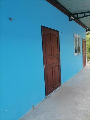 niebieska ściana z drewnianymi drzwiami w garażu w obiekcie Baan KaemSai w mieście Khao Lak
