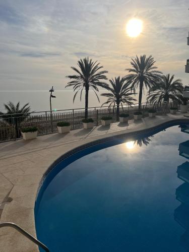 a swimming pool with palm trees in the background at Beachfront 3-bedroom apartment in Calafell