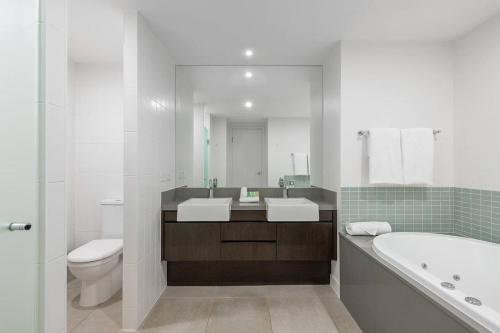 a bathroom with two sinks and a tub and a toilet at Swim-out Tropical Getaway by Four Mile Beach in Port Douglas