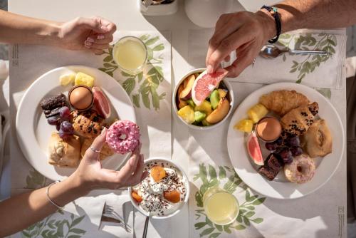 a table topped with plates of pastries and people holding donuts at Airis Boutique Hotel & Suites - For adults only in Kato Daratso