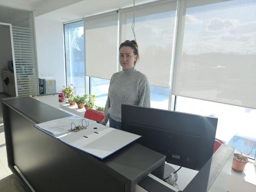 una mujer parada frente a un escritorio con un ordenador en Zack Apartments, en Murfatlar