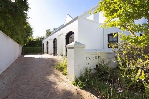 a white building with a brick sidewalk in front of it at Winelands Golf Lodges 29 in Stellenbosch