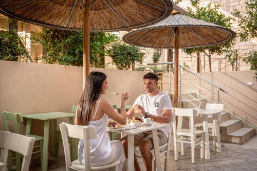 a man and woman sitting at a table eating food at Airis Boutique Hotel & Suites - For adults only in Kato Daratso