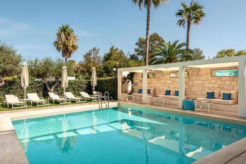 a swimming pool with chairs and palm trees at Airis Boutique Hotel & Suites - For adults only in Kato Daratso