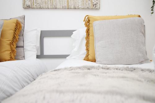 a bedroom with white bedding and yellow pillows at Centrally Located Spacious 2BR | CoHost Partners in Cardiff