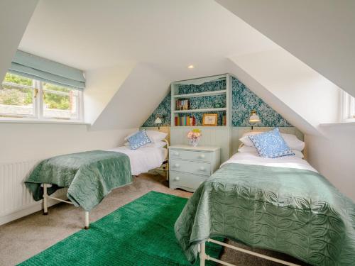 a attic bedroom with two beds and a green rug at 3 Bed in Nailsworth 78968 in Nailsworth