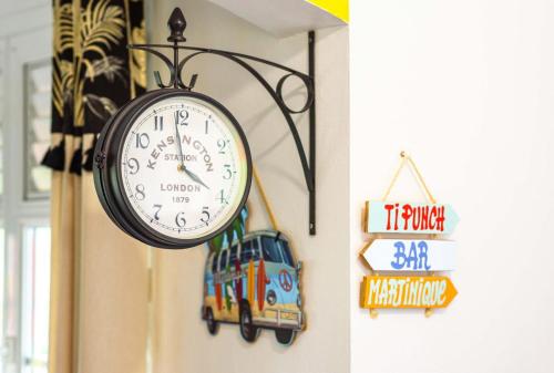 a clock hanging on a wall next to a sign at La maison créole in Rivière-Pilote
