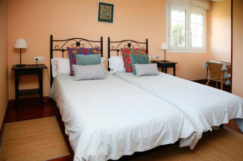a bedroom with a large white bed with pillows at Chalet con magníficas vistas al mar in Perlora