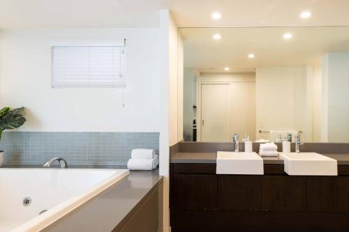 La salle de bains est pourvue de 2 lavabos et d'un grand miroir. dans l'établissement Sunny Swim-out Serenity with Direct Beach Access, à Port Douglas