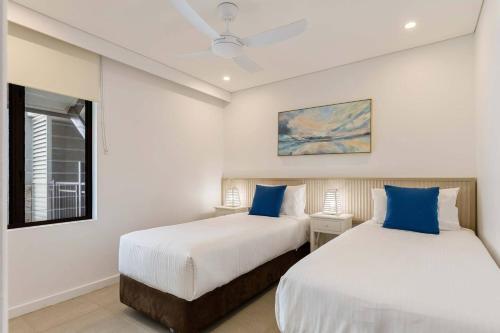 - 2 lits dans une chambre blanche avec des oreillers bleus dans l'établissement Sunny Swim-out Serenity with Direct Beach Access, à Port Douglas