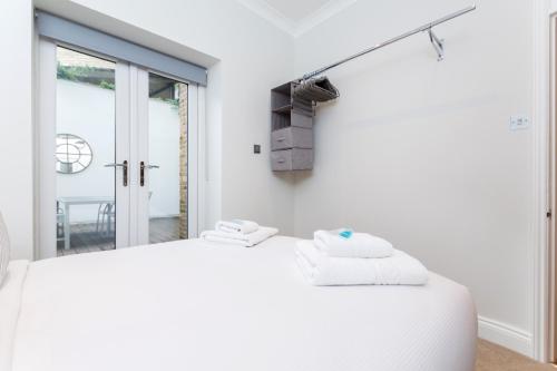 a bedroom with a white bed and a tv on the wall at Vibrant 1BR Apt wPrivate Decked Garden, Fast WIFI in London