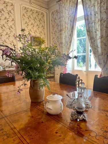 a dining room table with a vase of flowers on it at Chateau Le Plessis in Sémelay