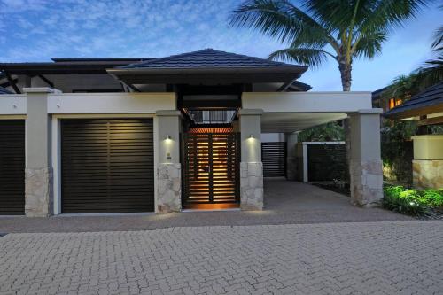 a house with a gate and a palm tree at The Villa at Temple - A Luxury Resort Hideaway in Port Douglas
