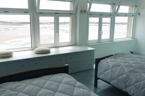 une chambre avec un lit et deux fenêtres dans l'établissement Appartement NOIRMOUTIER, à La Bernerie-en-Retz