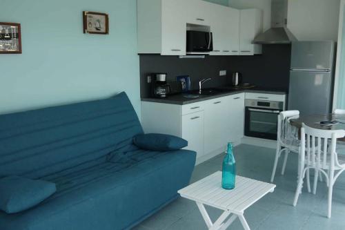 un salon avec un canapé bleu et une table dans l'établissement Appartement NOIRMOUTIER, à La Bernerie-en-Retz