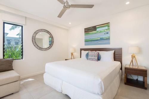 um quarto com uma cama branca e um sofá em Poolside Relaxation - Resort Retreat with Beach Access em Port Douglas