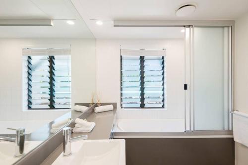 uma casa de banho com um lavatório e 2 janelas em Poolside Relaxation - Resort Retreat with Beach Access em Port Douglas