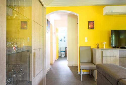 a room with yellow walls and a hallway with a chair at La maison créole in Rivière-Pilote