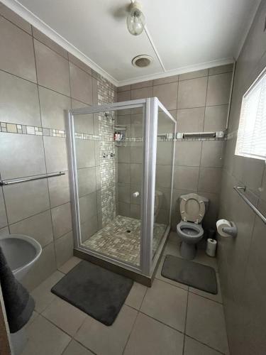 a bathroom with a shower with a toilet and a sink at Oppi Draai Guesthouse in Oudtshoorn