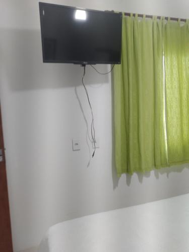 einen Fernseher an einer Wand neben einem grünen Vorhang in der Unterkunft Casa Aconchegante in Cabo Frio