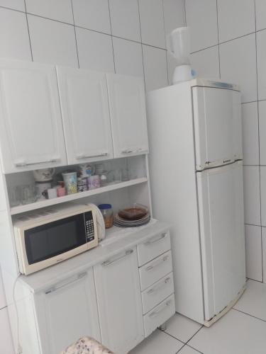eine weiße Küche mit einer Mikrowelle und einem Kühlschrank in der Unterkunft Casa Aconchegante in Cabo Frio