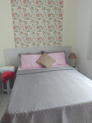 ein Schlafzimmer mit einem Bett mit rosa Kissen in der Unterkunft Casa Aconchegante in Cabo Frio