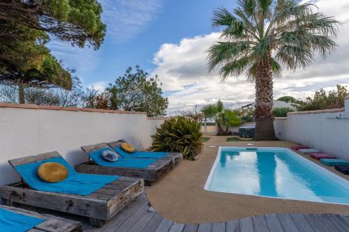 une cour avec une piscine, deux chaises et un palmier dans l'établissement VILLA HESTIA - Piscine Privée, au Cap d'Agde