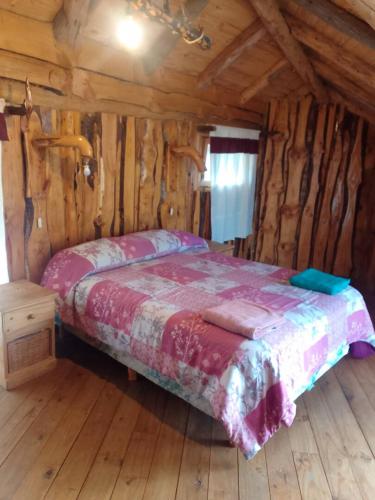 um quarto com uma cama num chalé de madeira em CABAÑAS EL PALENQUE em Esquel