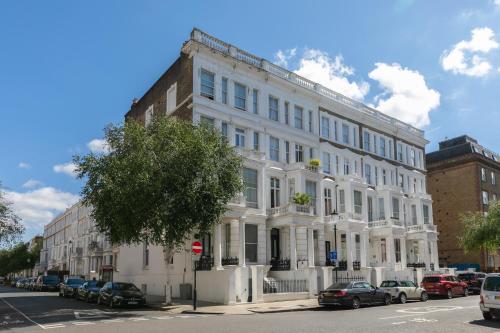 een wit gebouw met auto's ervoor geparkeerd bij Modern Kensington Apartments in Londen