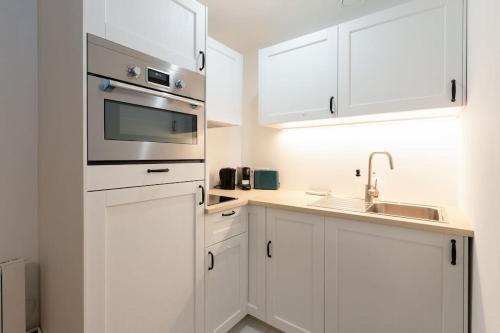 une cuisine blanche avec des armoires blanches et un évier dans l'établissement Le capucin, à Metz