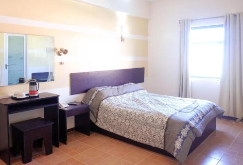 una camera con letto, tavolo e specchio di Metro Park Hotel Mandaue a Cebu City