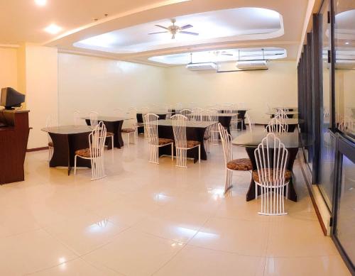 uma sala de jantar com mesas e cadeiras e um tecto em Metro Park Hotel Mandaue em Cebu