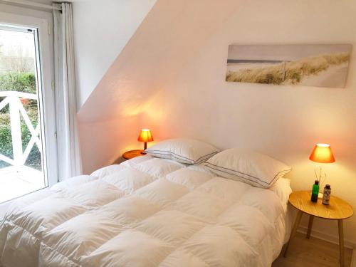 een wit bed in een kamer met een raam bij Voile et Plage, Villa 3 étoiles à La Trinité sur Mer in La Trinité-sur-Mer