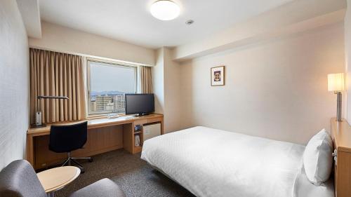 a hotel room with a bed and a desk with a computer at Daiwa Roynet Hotel Akita in Akita