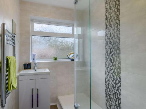 a bathroom with a glass shower and a sink at 3 Bed in Sheringham 86262 in Sheringham