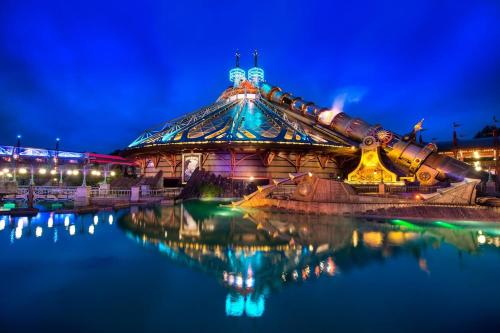 a building with a reflection in the water at night at Magic Studio - Disneyland Paris Shopping village 9 minutes in Chessy