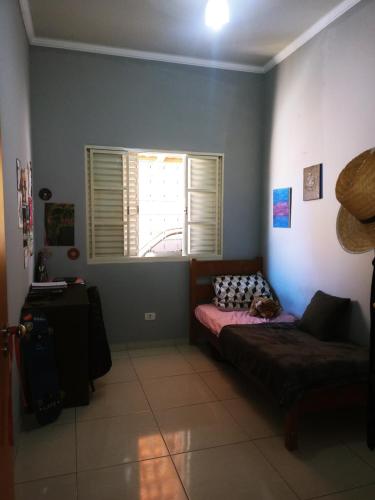 a living room with a bed and a window at Casa da pri in São João Batista do Glória