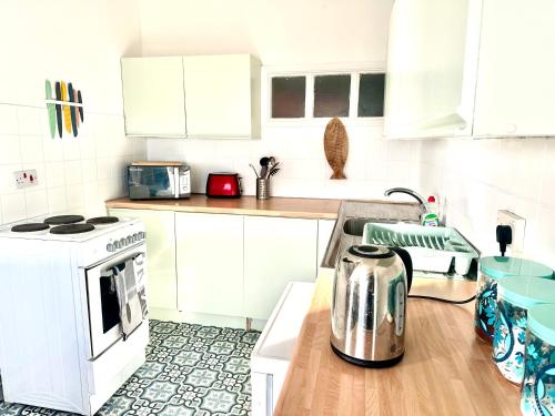 a kitchen with white cabinets and a toaster on a counter at The Captains Lookout-Sleeps 6! in St. Leonards