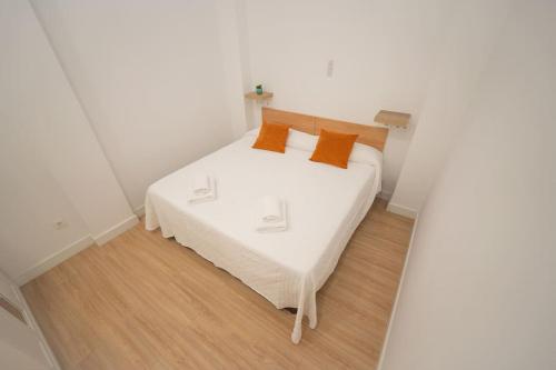 - une chambre avec un lit blanc et des oreillers orange dans l'établissement Apartamento a estrenar en San Bernardo, à Séville